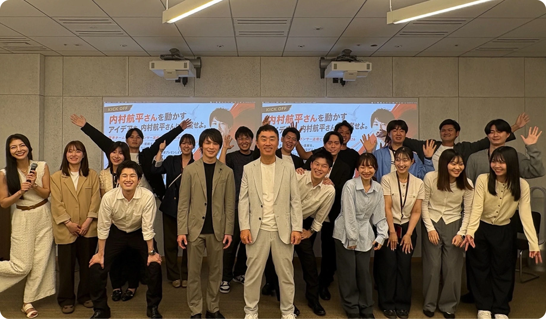 社内ビジネスコンテストの会場で手を振る参加者たち